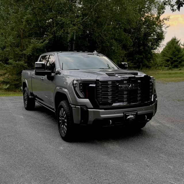 A freshly detailed dark grey GMC Denali HD pickup on a driveway