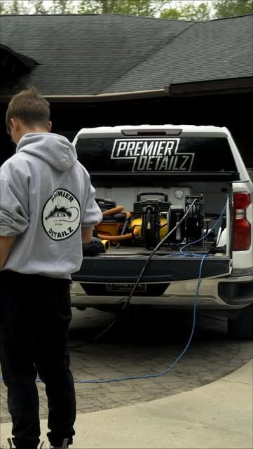 Landon Scofield loading equipment into a pickup with the Premier Detailz name on the rear window