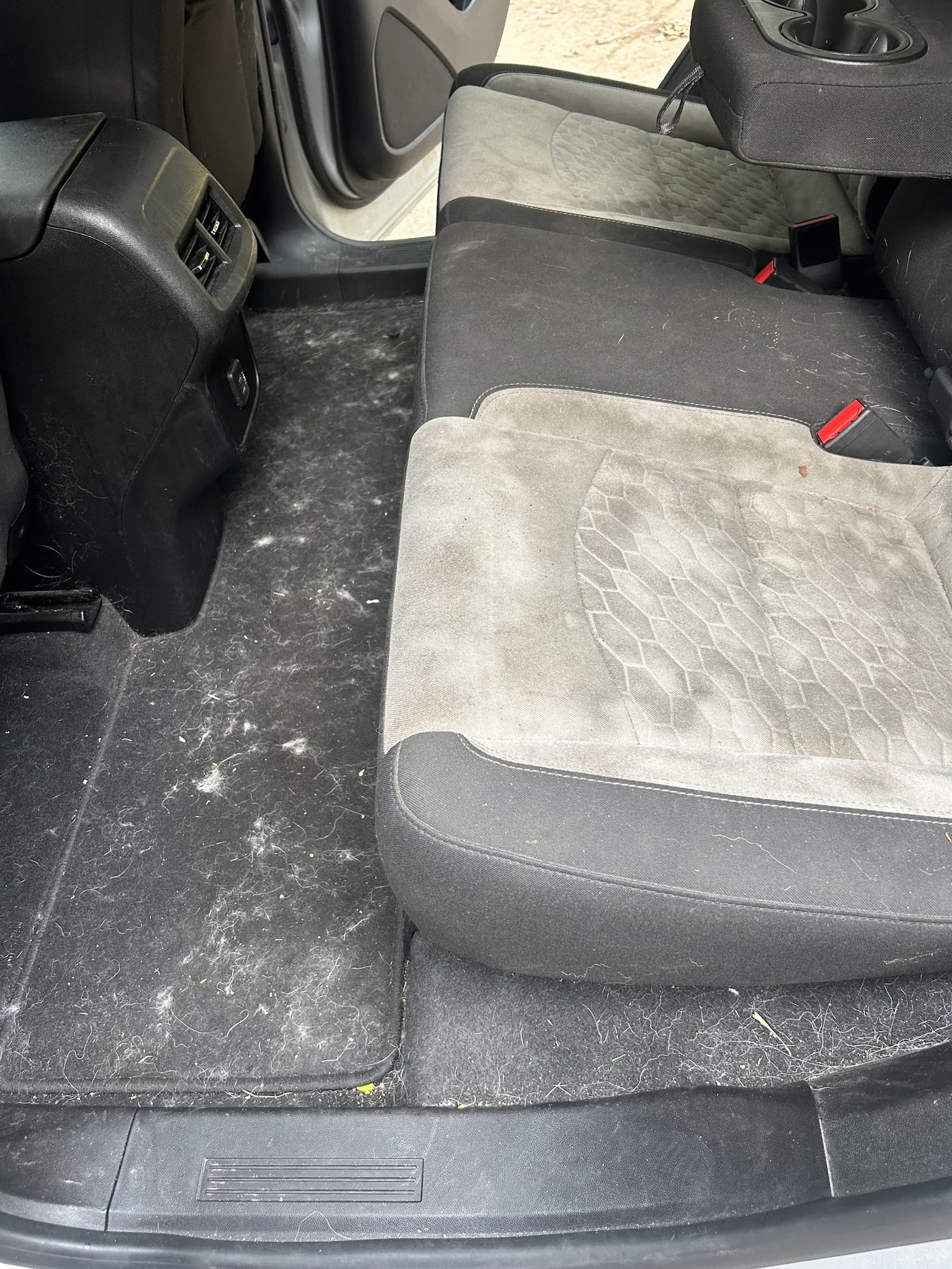 A dirty rear bench seat and floor mat before detailing